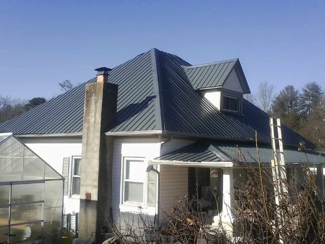 Dark blue standing seam metal roof on a white farmhouse with dormer — Slate & Tile Roof Repair by Roofing Brothers in Challis