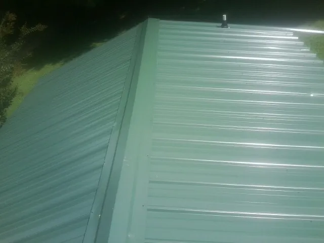 New green metal panels meeting at the ridge of a roof — Flat Roof Repair work by our crew in Challis
