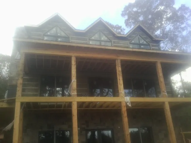 Dormers and porch framing on a large log home under construction — Roof Coating work by our crew in Challis
