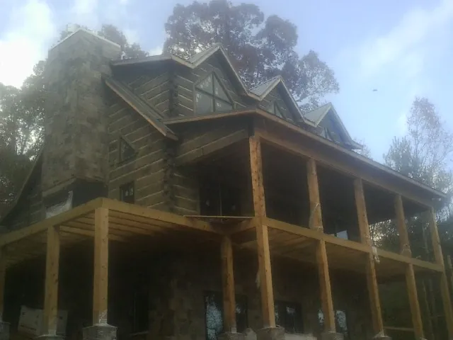 Stone chimney and dormers on a large log home with a timber porch in Challis