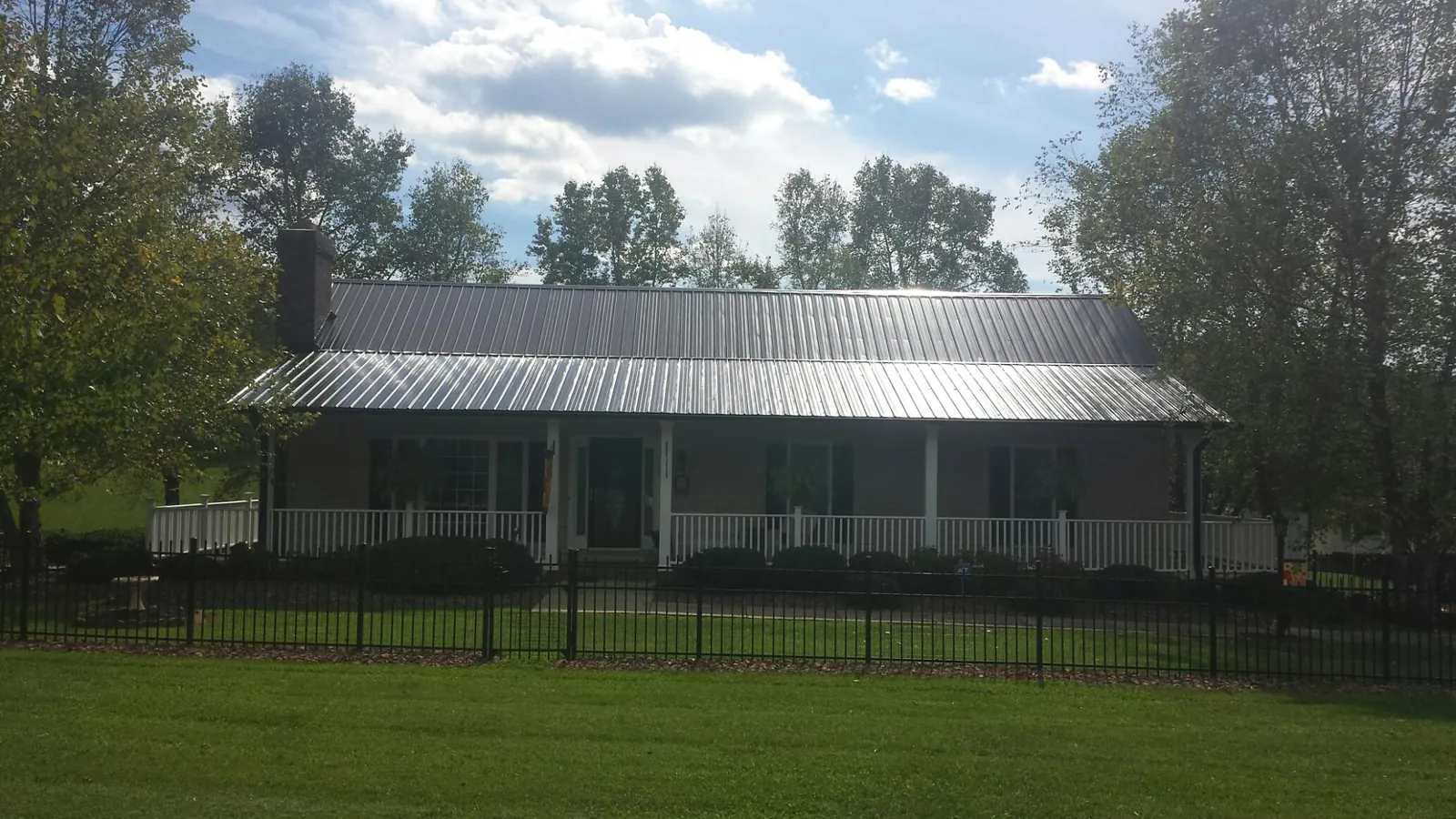 Gray metal roof on a brick ranch with a full width front porch — Gutter Guard Installation work by our crew in Challis