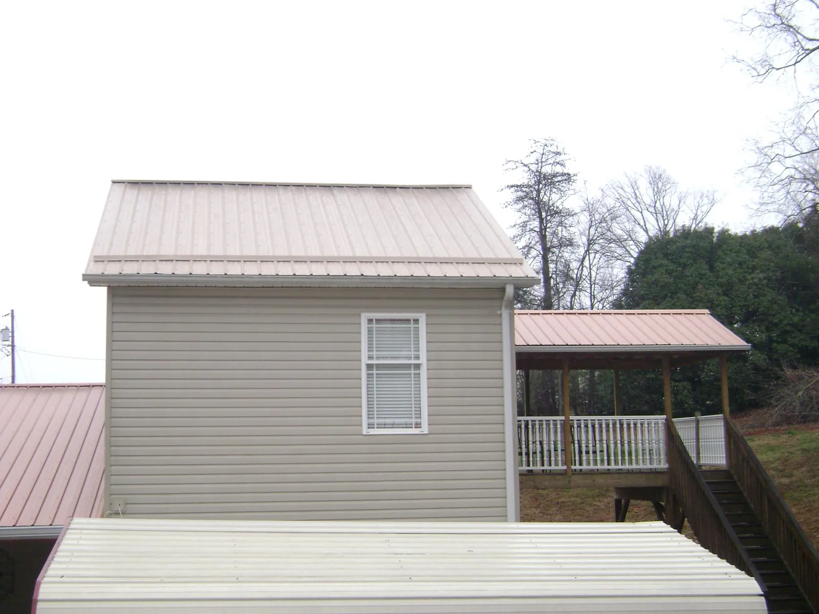 Tan metal roofs on a two story addition and attached porch, from a Roof Replacement job in Challis